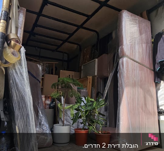 משאית פתוחה עם רהיטים וארגזים עטופים בניילון